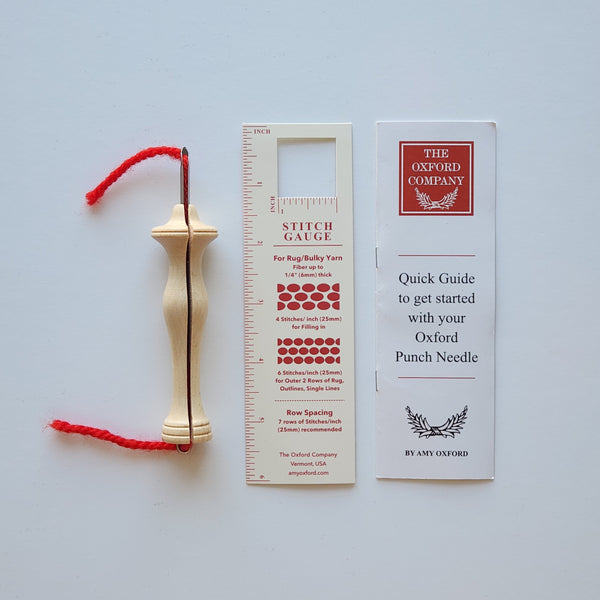 Gold punch needle with red thread and two guides on a light gray background