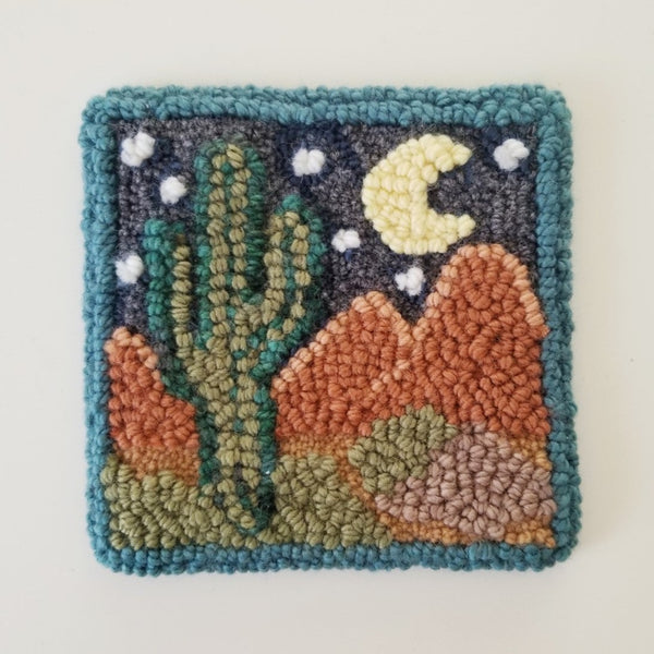 a completed punch needle pattern showing a desert landscape and cactus at night