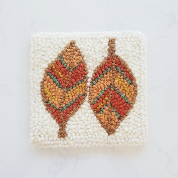 punch needle design showing two leaves finished in red orange and green wool