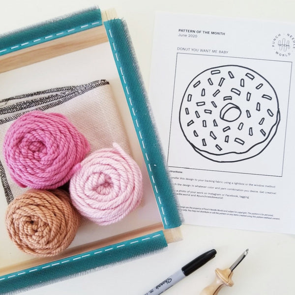 punch needle frame, yarn and donut pattern printout seen from above the table